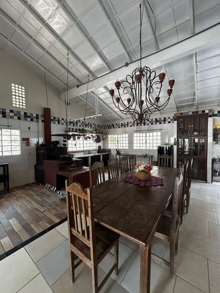 Cozinha caipira rústica e equipada com fogão à lenha e mesa para refeições em grupo